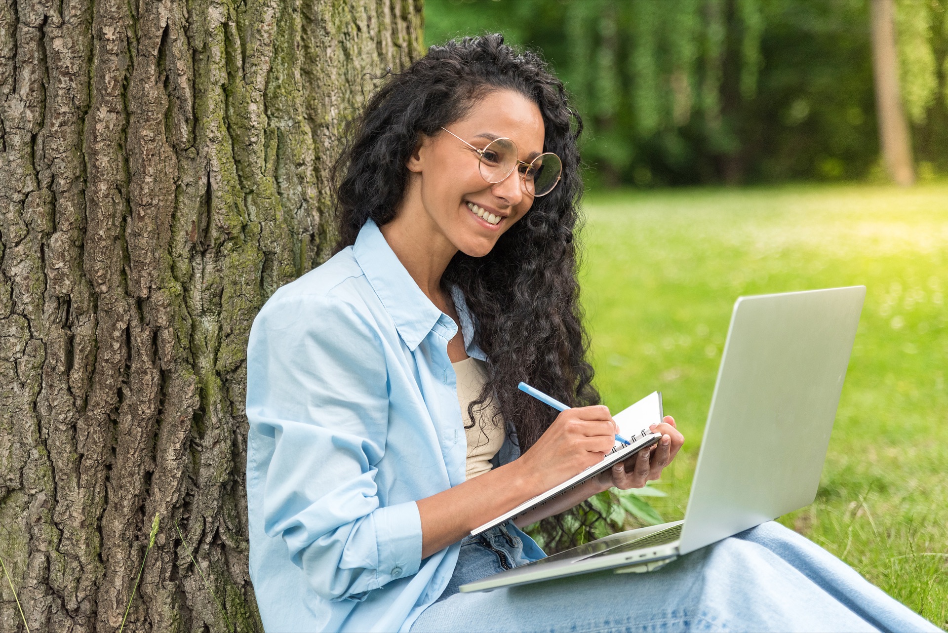 Frau sitzt am Baum mit Laptop – Weiterbildung flexibel gestalten